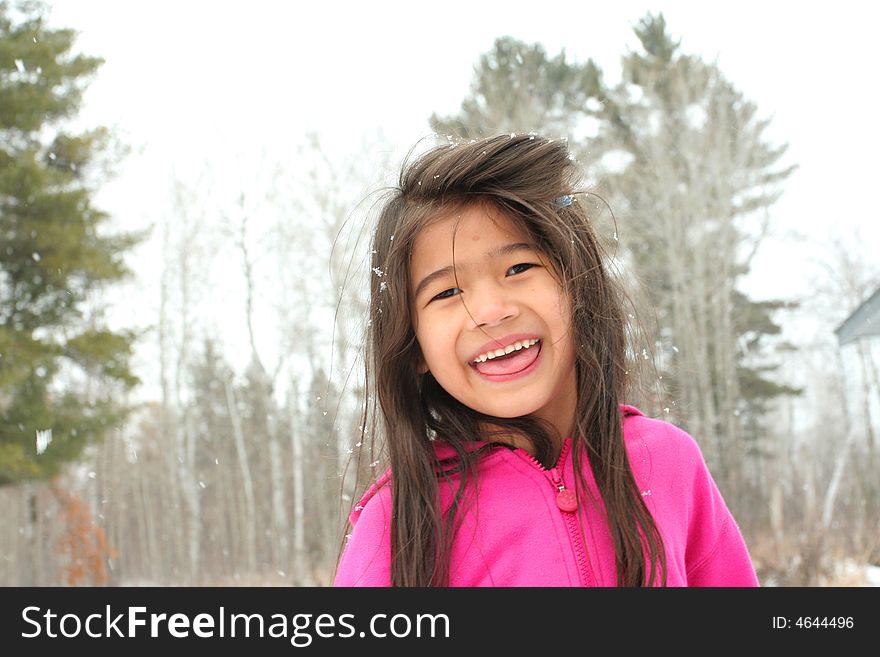 Child sticking out tongue while playing outdoors in winter