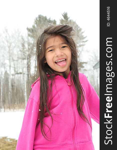 Child sticking out tongue while playing outdoors in winter
