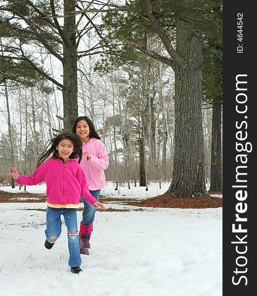Two little girls running happily through the snow in winter. Two little girls running happily through the snow in winter