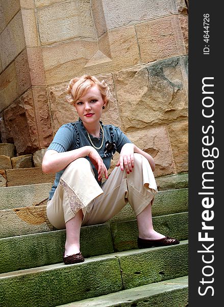 Young blond woman sitting on stone steps. Young blond woman sitting on stone steps