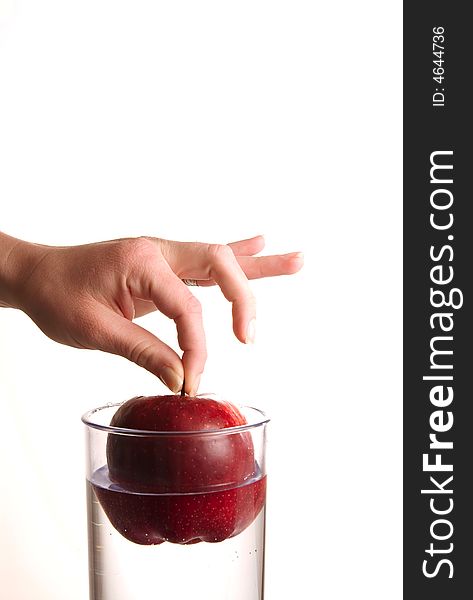 A hand dropping an apple in glass water. A hand dropping an apple in glass water