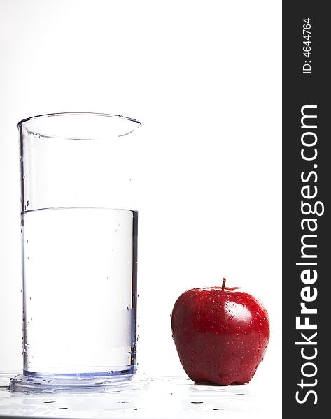 A glass of water next to a red delicious apple. A glass of water next to a red delicious apple