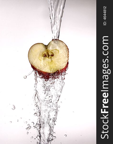Water pouring  and splashing over a red delicious apple on white. Water pouring  and splashing over a red delicious apple on white