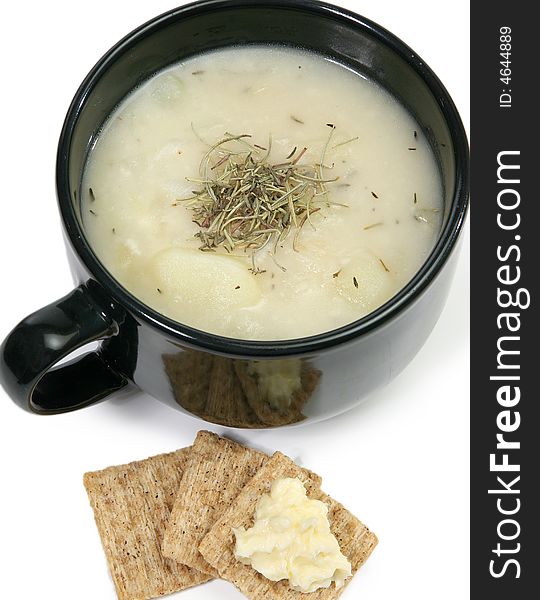 Bowl of homemade herb potato soup and wheat crackers with butter. Bowl of homemade herb potato soup and wheat crackers with butter.