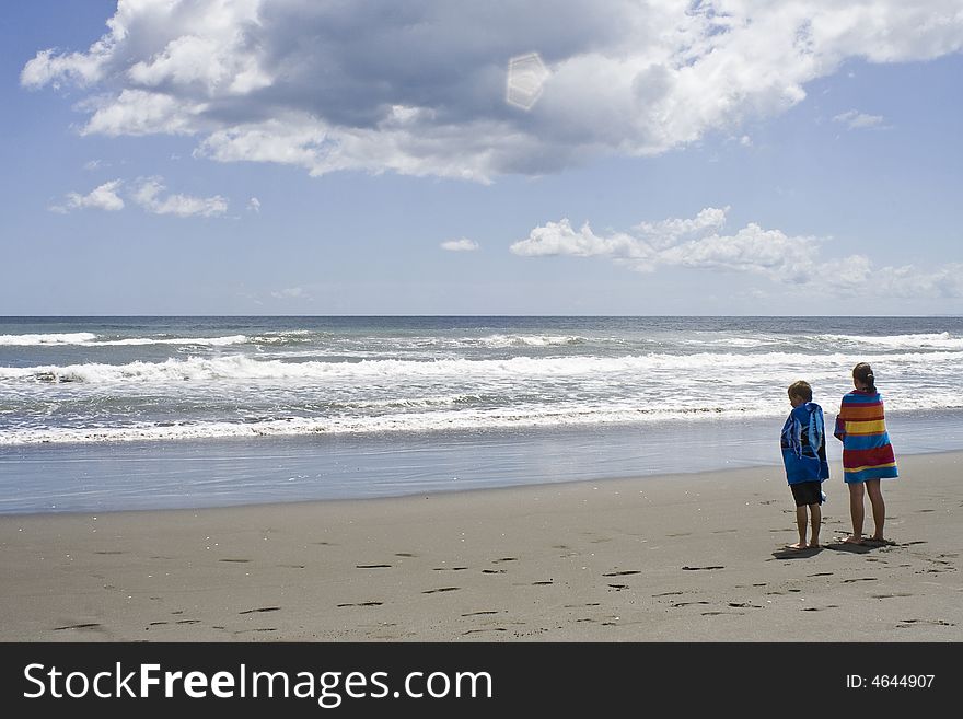 Children looking out to sea wrapped in towels after a swim