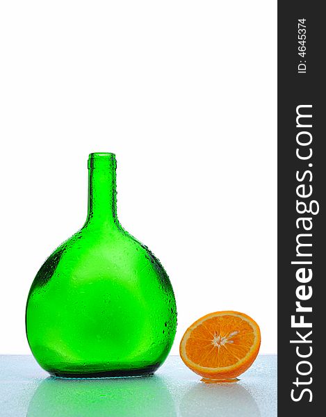 Green bottle with water drops and fresh orange. Green bottle with water drops and fresh orange