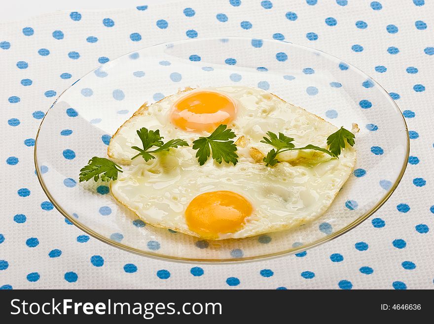 Food series: fried eggs with parsley on the glassy plate
