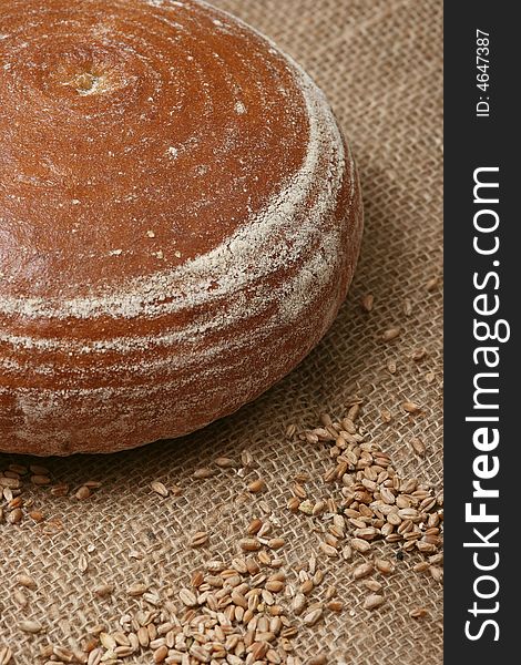 A closeup of a round loaf of bread with wheat grains. A closeup of a round loaf of bread with wheat grains.