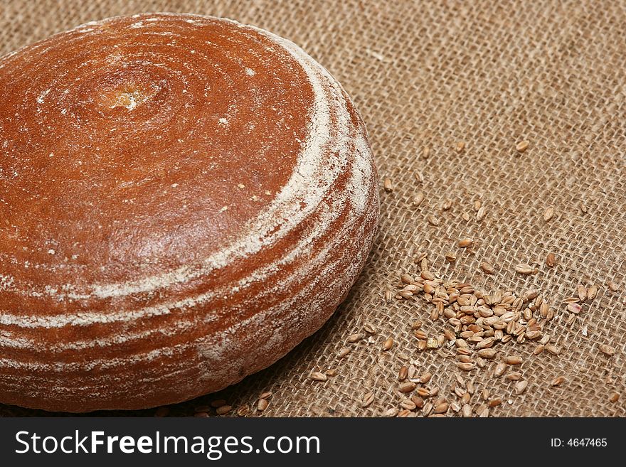 A closeup of a round loaf of bread with wheat grains. A closeup of a round loaf of bread with wheat grains.