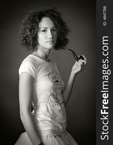 Portrait of a woman with curled hair smoking pipe in studio on a black background. Portrait of a woman with curled hair smoking pipe in studio on a black background