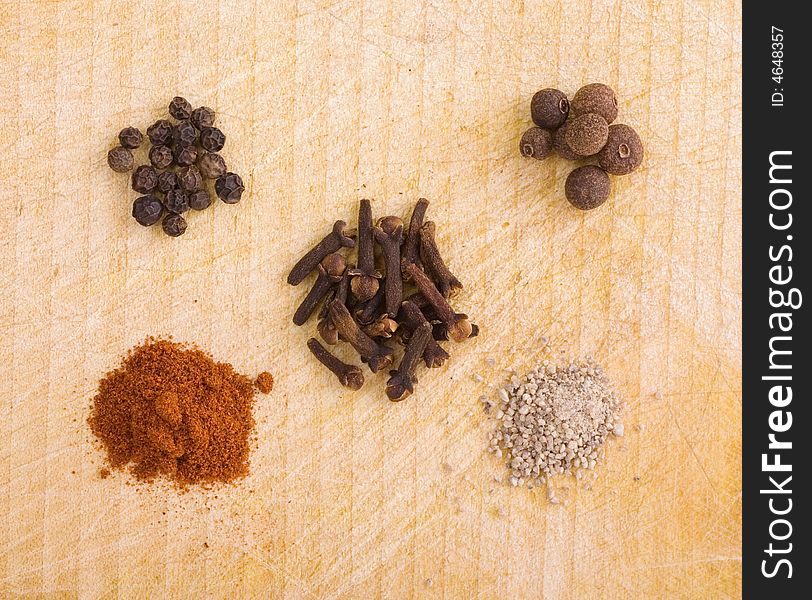 Five piles of spice grains on a wooden board - photo from the top. Five piles of spice grains on a wooden board - photo from the top