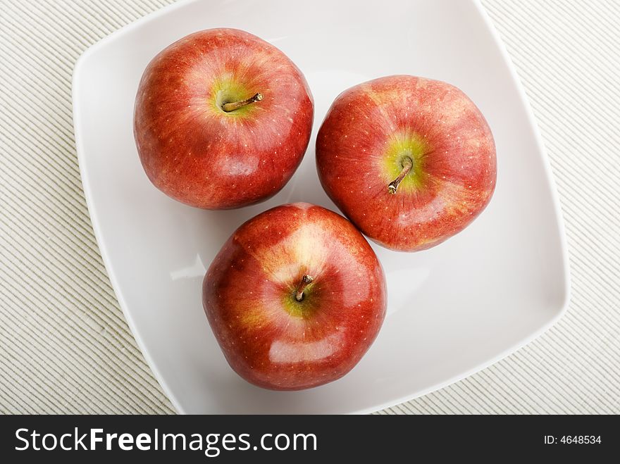 Three apples on white plate