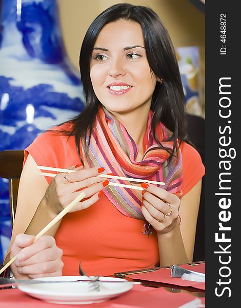 Portrait beautiful woman eats with the chopsticks at restaurant. Portrait beautiful woman eats with the chopsticks at restaurant