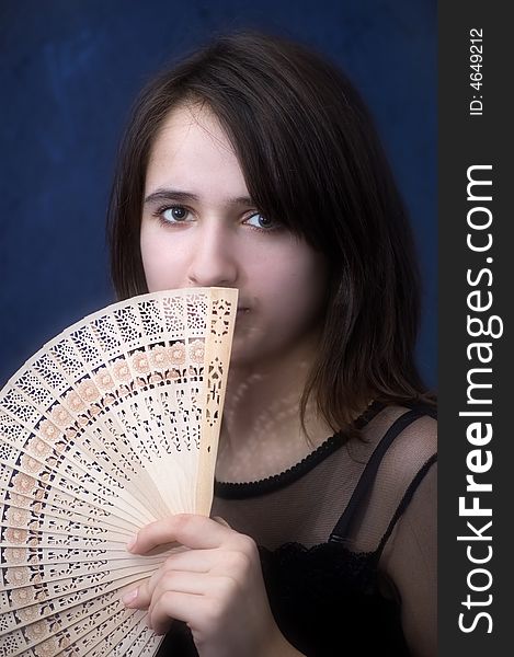 Closeup photo of the brunette with  fan on a dark blue background. Closeup photo of the brunette with  fan on a dark blue background