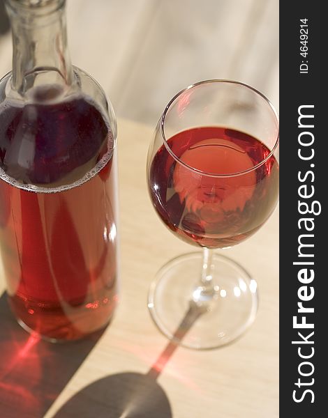 Red wine and glass on wooden table sitting in spring sunshine.