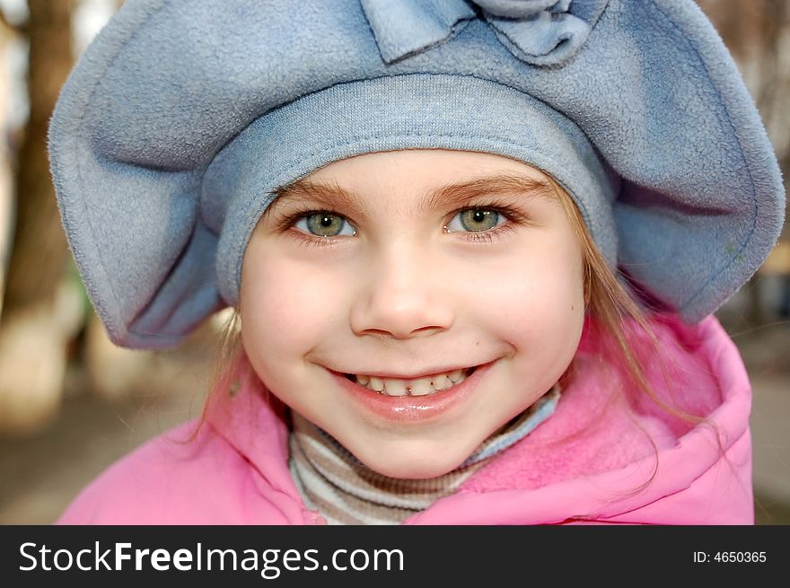 Happy smiling little girl wearing big blue hat in the street. Happy smiling little girl wearing big blue hat in the street
