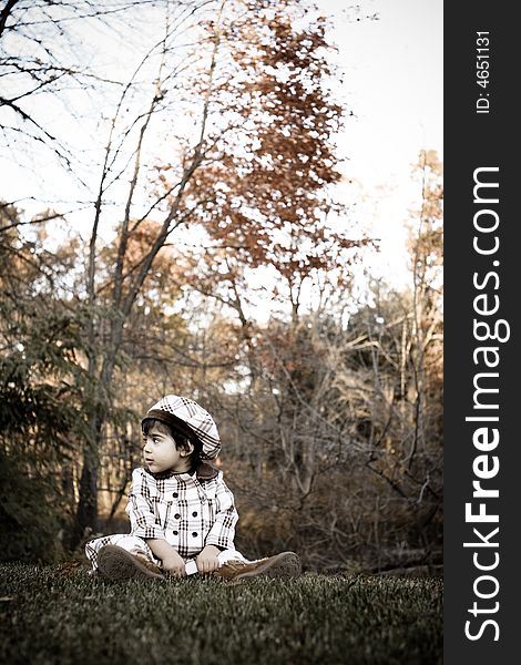 Two year old sitting on grasses with beautiful fall colors in the background. Two year old sitting on grasses with beautiful fall colors in the background