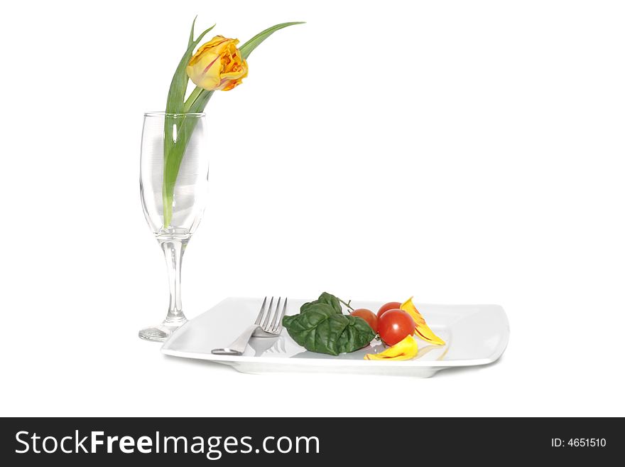 Still life of vegetables on a plete and flower in a glass. Still life of vegetables on a plete and flower in a glass