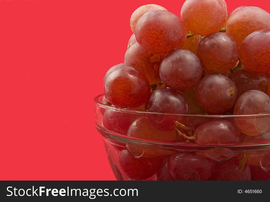 Red grapes in glass bowl on red background. Red grapes in glass bowl on red background.