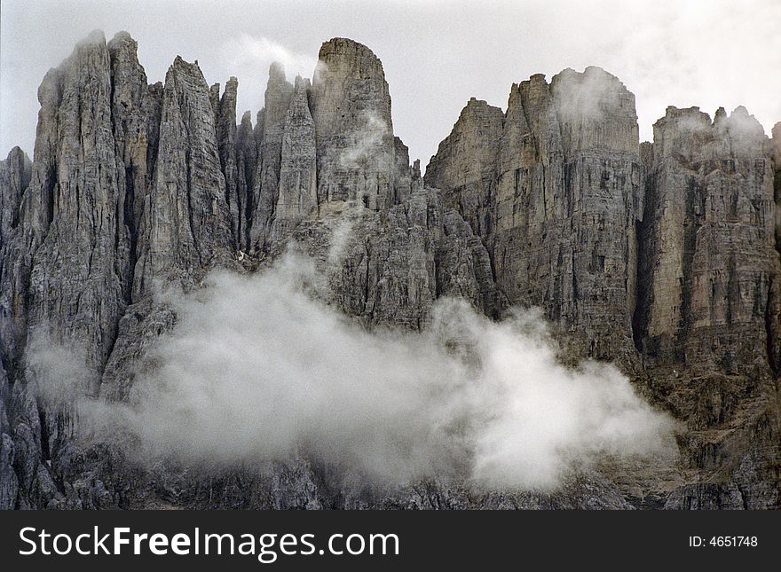 View of Dolomites mountains in Italian Alps showing chalk rocks in an amazing stone barrier on a cloudy day.