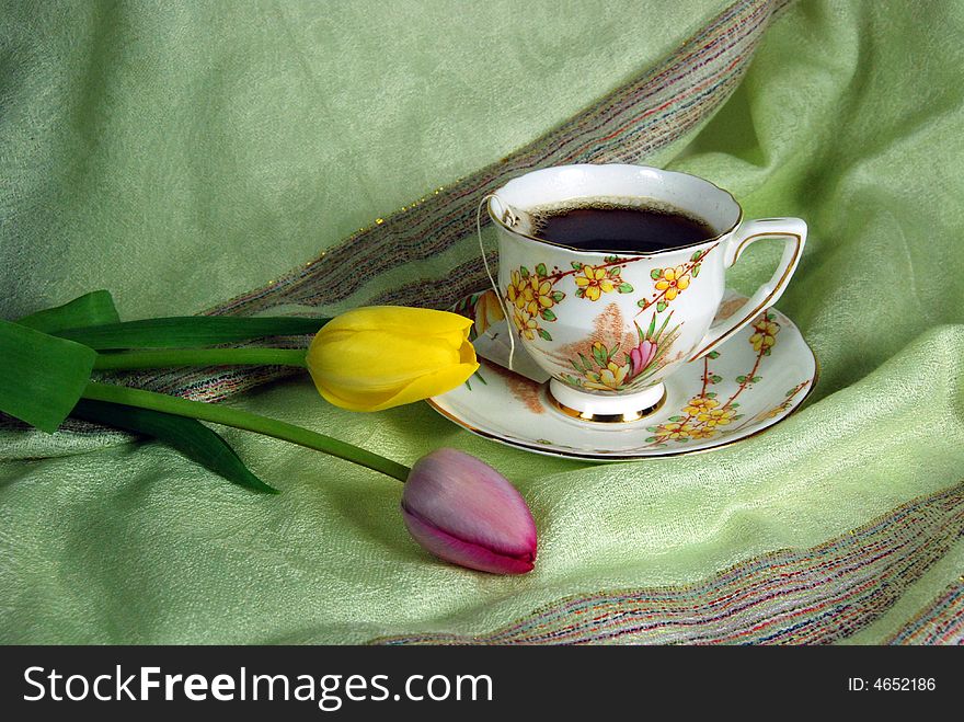 Antique tea cup and saucer with spring tulips on linen. Antique tea cup and saucer with spring tulips on linen.