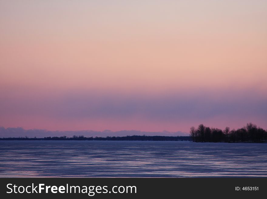 A frozen bay in northern New York is colored as the Sun sets nearby. A frozen bay in northern New York is colored as the Sun sets nearby.