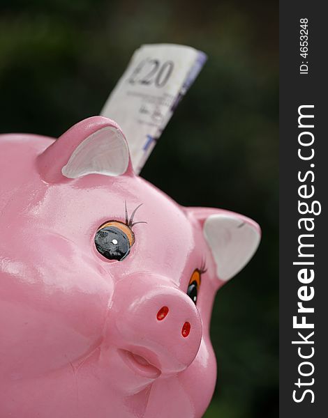 Pink piggy bank with a bank note about to pushed into the savings hole. Pink piggy bank with a bank note about to pushed into the savings hole