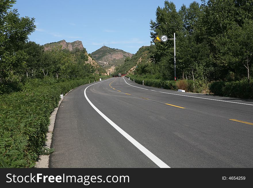 Rural mountain road with  bend showing skid marks， the hills in a blue sky. Rural mountain road with  bend showing skid marks， the hills in a blue sky.