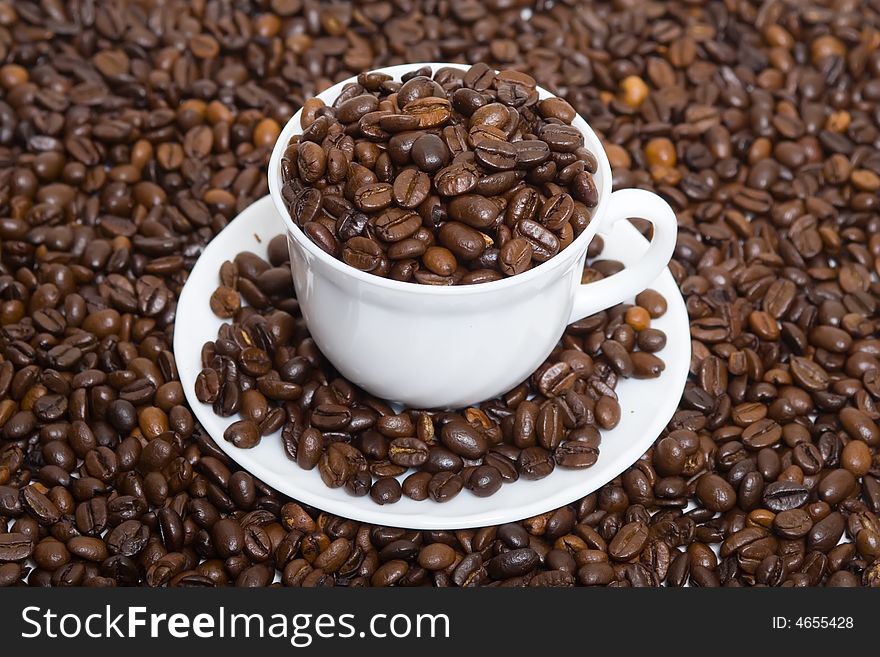 The cup full of coffee beans at coffee background. The cup full of coffee beans at coffee background