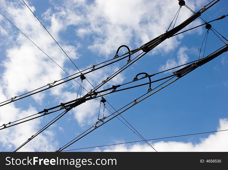 Suspended tramway power cables against blue sky with clouds. Suspended tramway power cables against blue sky with clouds