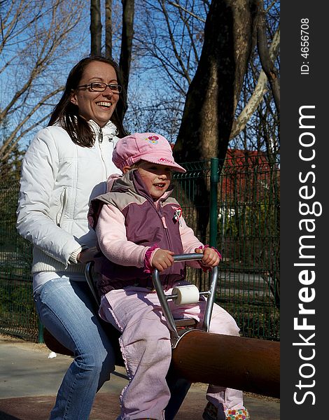 Young girl and children smiling in tandem seesaw.