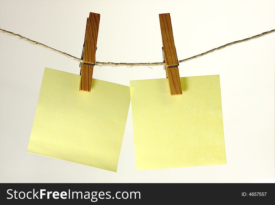 Two sticky note hanging on a peg from a line. Two sticky note hanging on a peg from a line