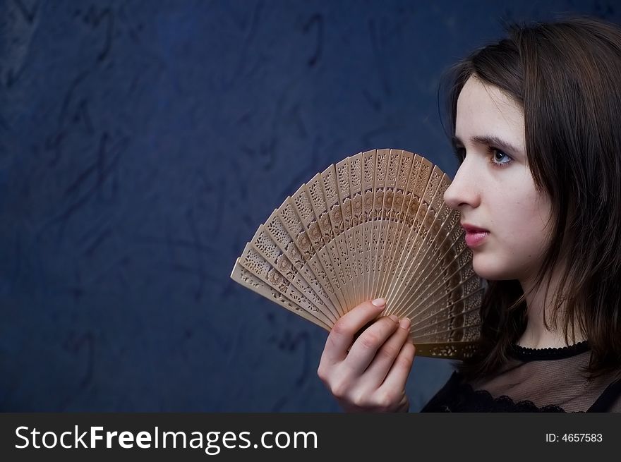 Closeup photo of the brunette with  fan on a dark blue background. Closeup photo of the brunette with  fan on a dark blue background