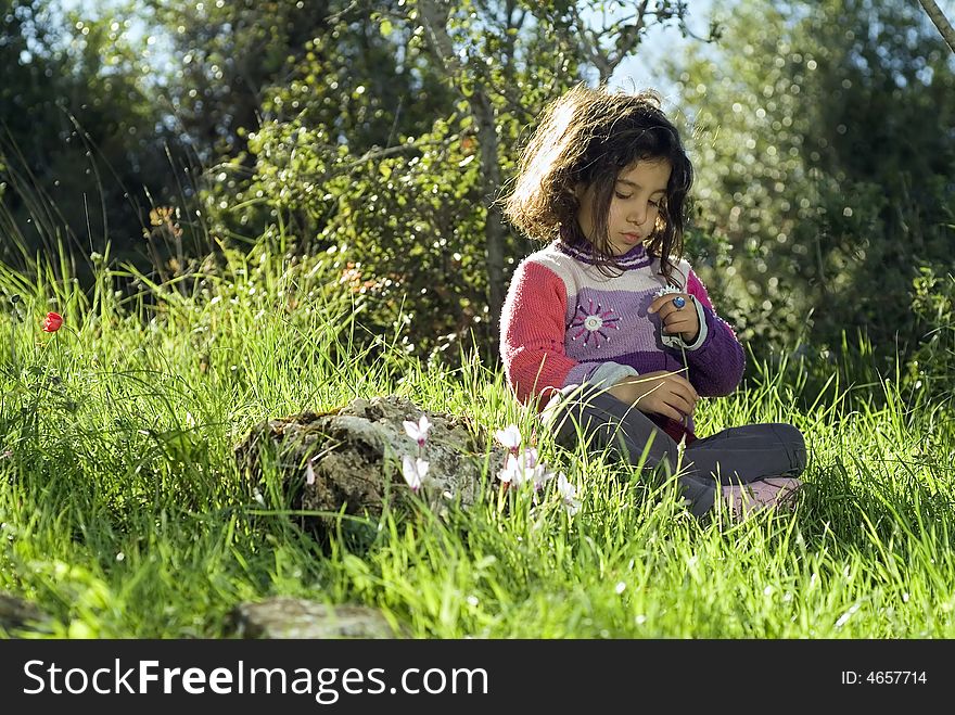 Girl sitting in wild grass holding a white flower. Girl sitting in wild grass holding a white flower