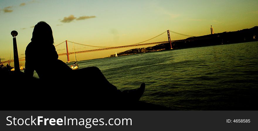 Silhouette of a woman sitting on the harbour at sunset. Silhouette of a woman sitting on the harbour at sunset