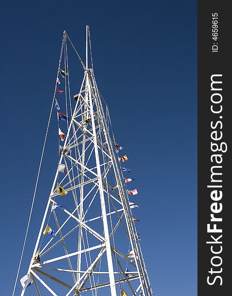 A white tower with nautical flags on ropes against a blue sky. A white tower with nautical flags on ropes against a blue sky