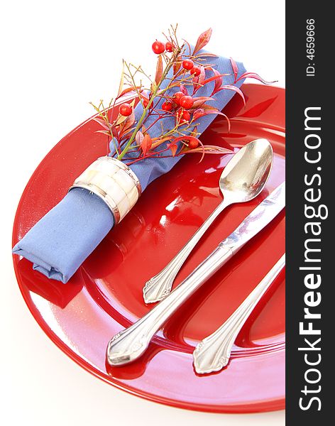 Elegant table setting in red and blue, with fresh sprigs of leaves and berries