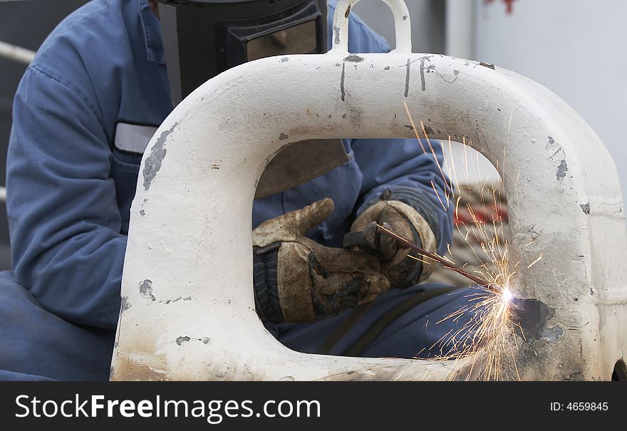 A welder working at shipyard during day. A welder working at shipyard during day