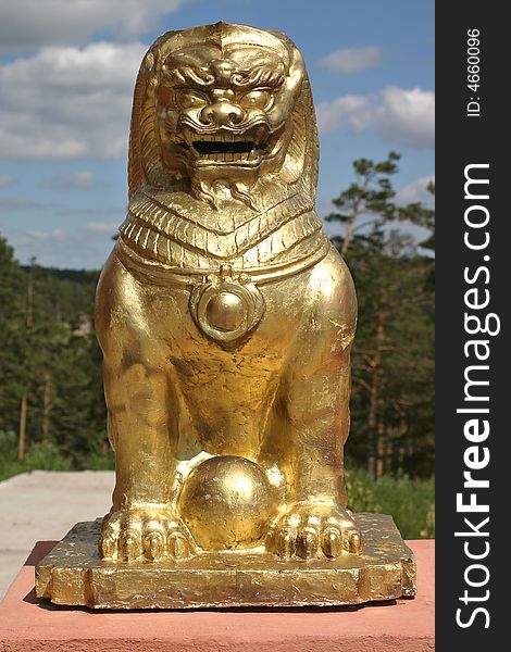 A buddhist lion in front of a forest, near a temple in siberia