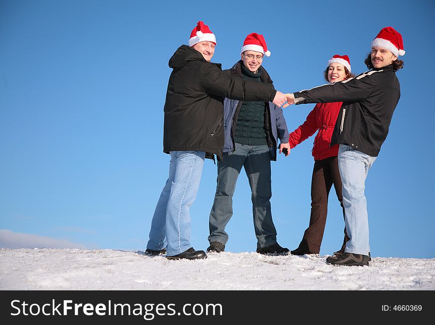 Four friends on snow in santa claus hats