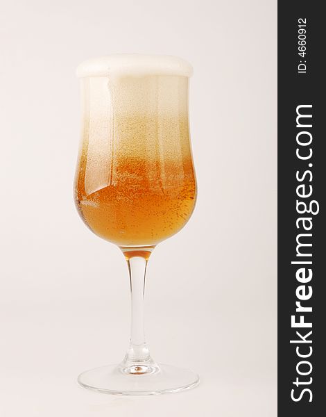 A glass goblet with foaming beer. A glass goblet with foaming beer.