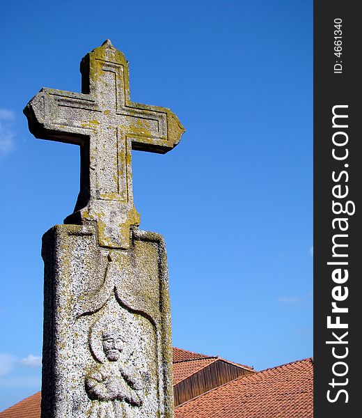 Stone cross landmark over roofs in a blue sky