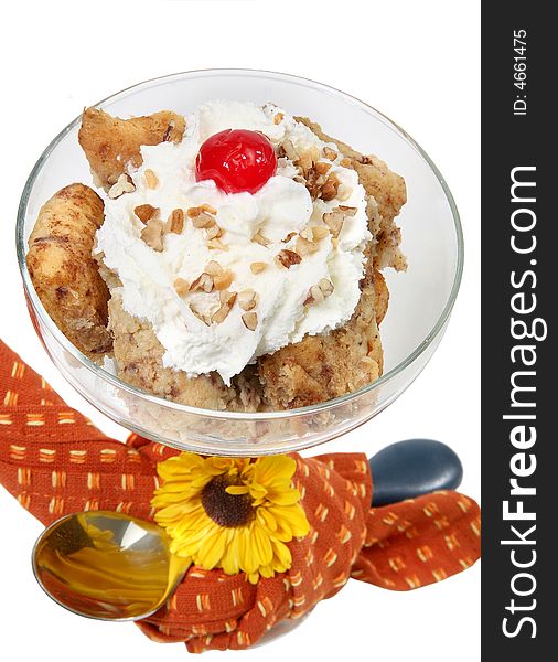 Homemade cinnamon roll bread pudding in glass with spoon and flower over white.