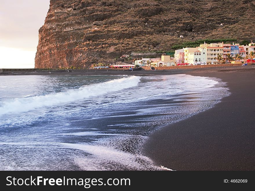 Volcanic beach of La Palma, village in the water reflection of Atlantic ocean with long surf. Volcanic beach of La Palma, village in the water reflection of Atlantic ocean with long surf