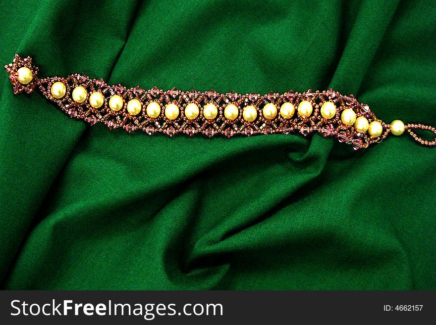 Bracelet made with pearls and beads on green background. Bracelet made with pearls and beads on green background