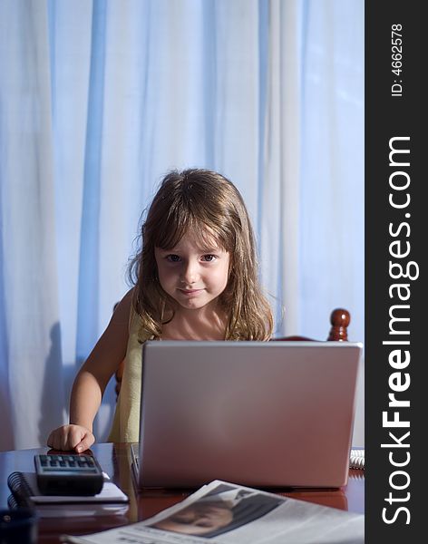 Little girl behind a laptop in a home office. Little girl behind a laptop in a home office