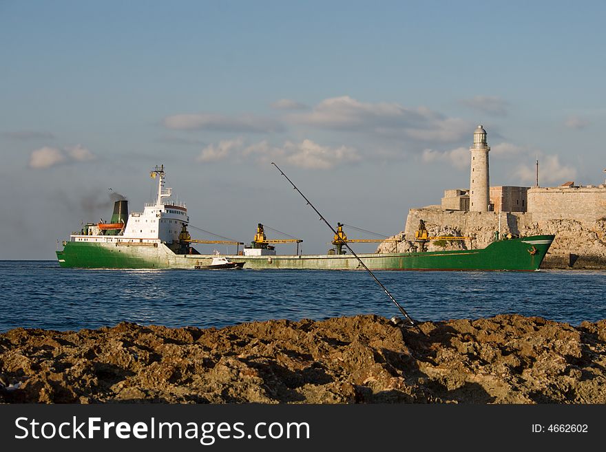 Cargo ship entering the bay of Havana with the lighthouse of El Morro in a background