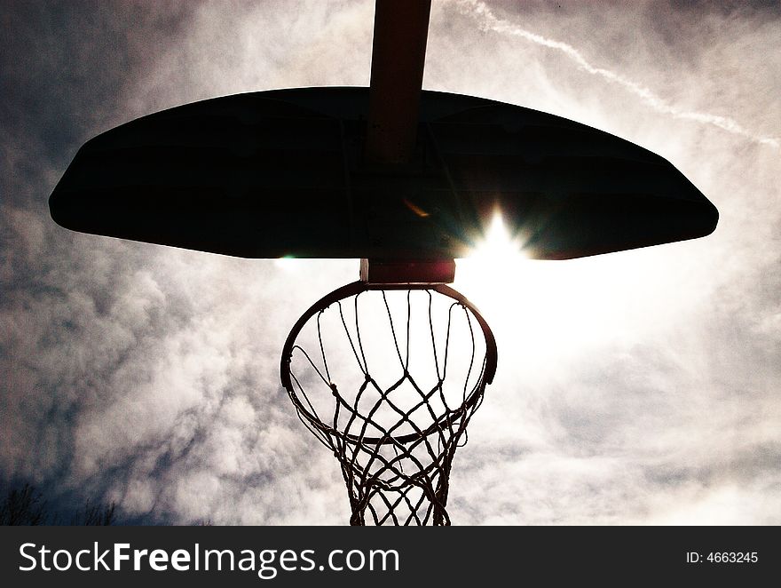 Basketball hoop shot from underneath. Backlit with sun coming through. Basketball hoop shot from underneath. Backlit with sun coming through.