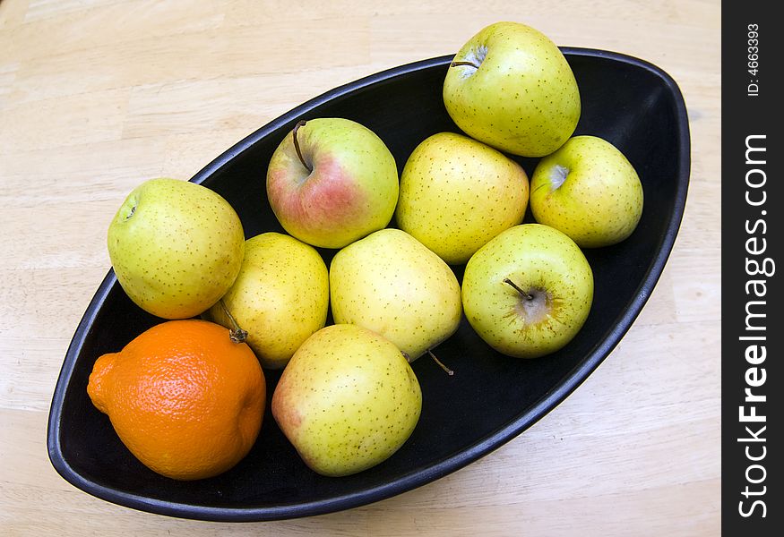 Black Japanese vase with apples and tangerine served at wooden table