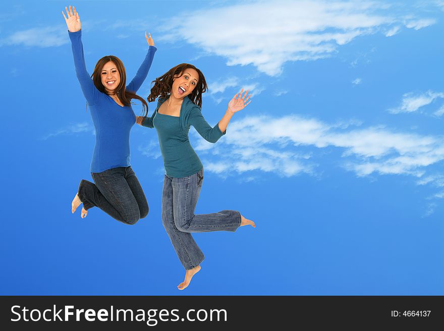 Two girls having fun by throwing themselves up in the blue sky with silly expression. Two girls having fun by throwing themselves up in the blue sky with silly expression